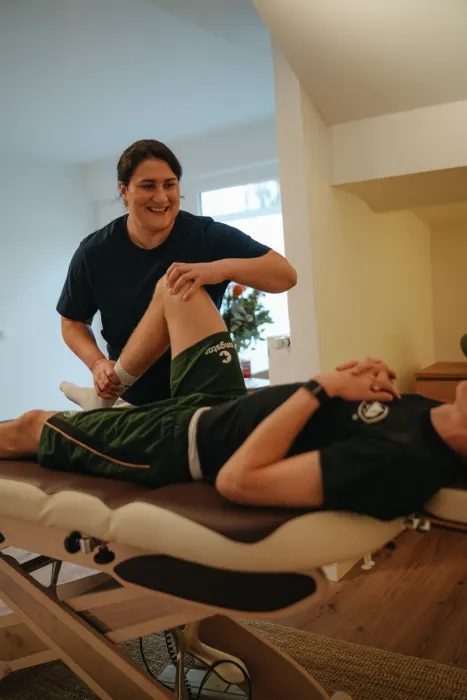 Dr. Nika Heidari untersucht das Knie eines Sportlers auf der Behandlungsliege
