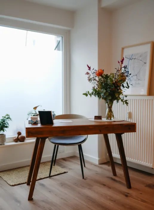 Heller Besprechungstisch mit Blumen am Fenster der Praxis