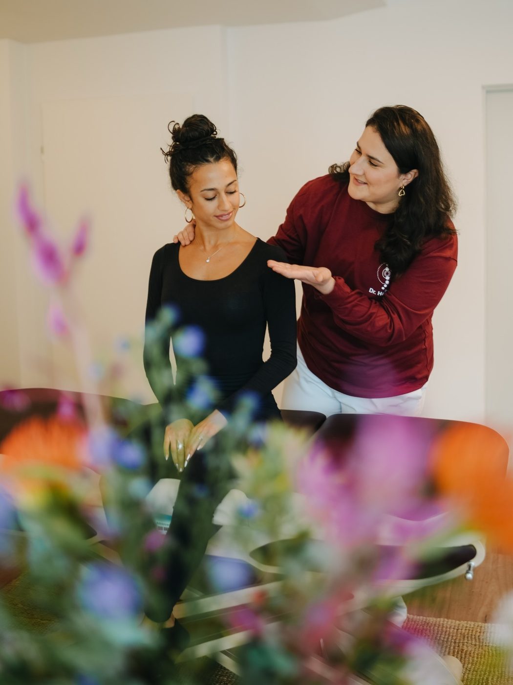 Dr. Nika Heidari untersucht Nacken und Schulter einer stehenden Patientin